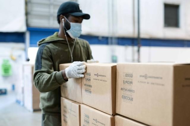 A volunteer stacks International 纸 community boxes at a food bank